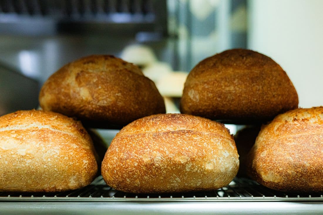 Loaves of crusty bread cooling on a rack in a bakery