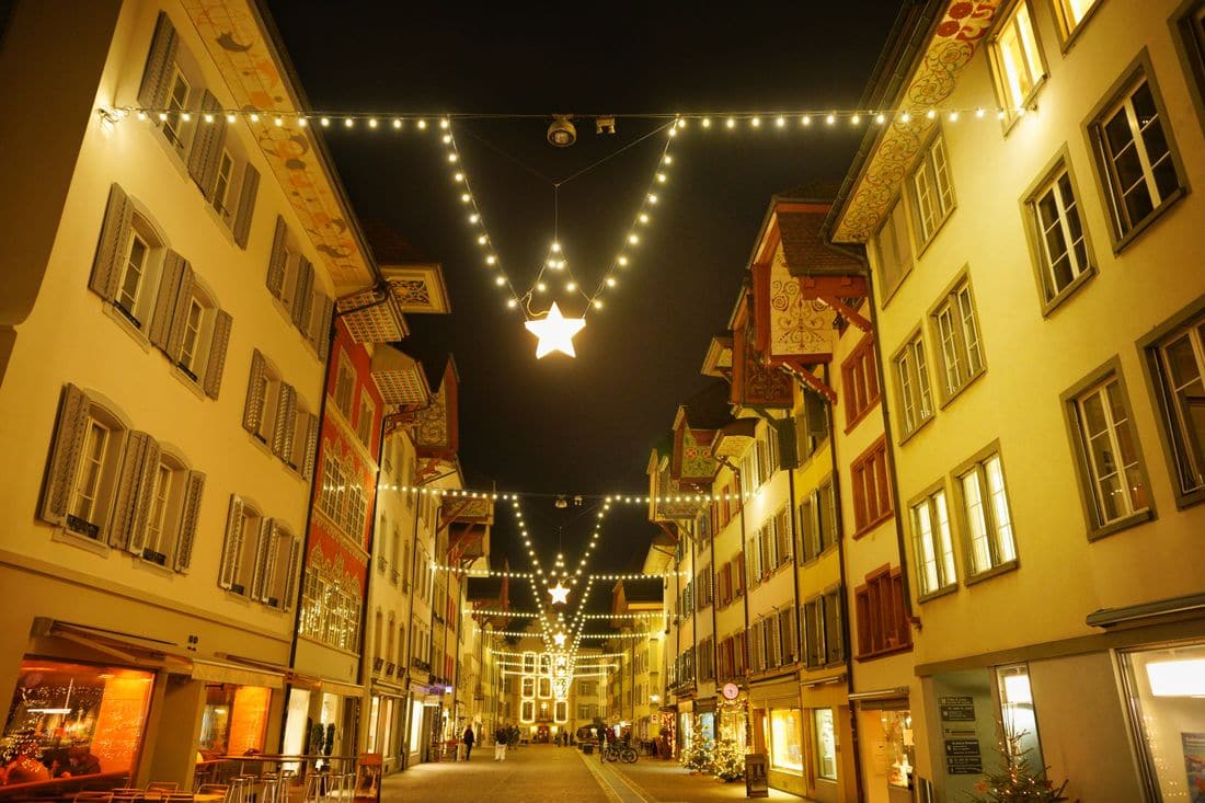 A shopping street at night with strings of lights and a lit star hung between the buildings