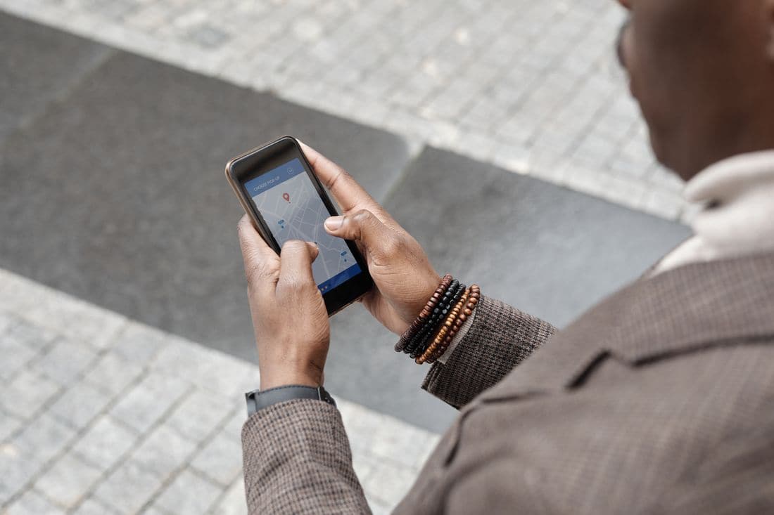 Hands holding a phone with a map open above a paved city street