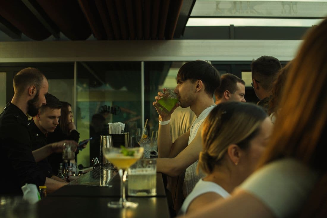 A busy bar with bartenders working behind the counter and customers drinking