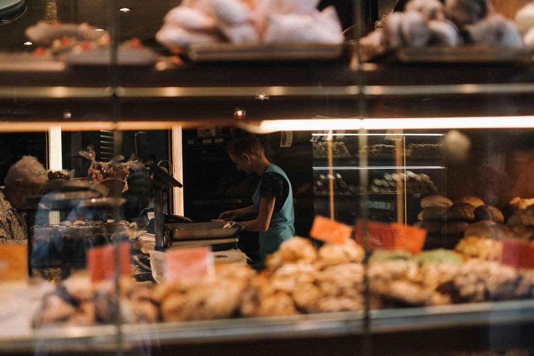 A baker working behind a glass counter of pastries and bread