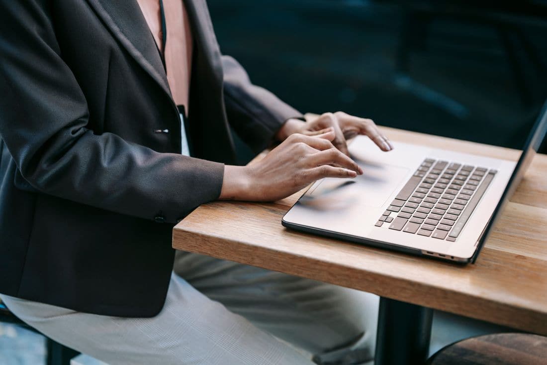 Hands typing on a laptop at a wooden table