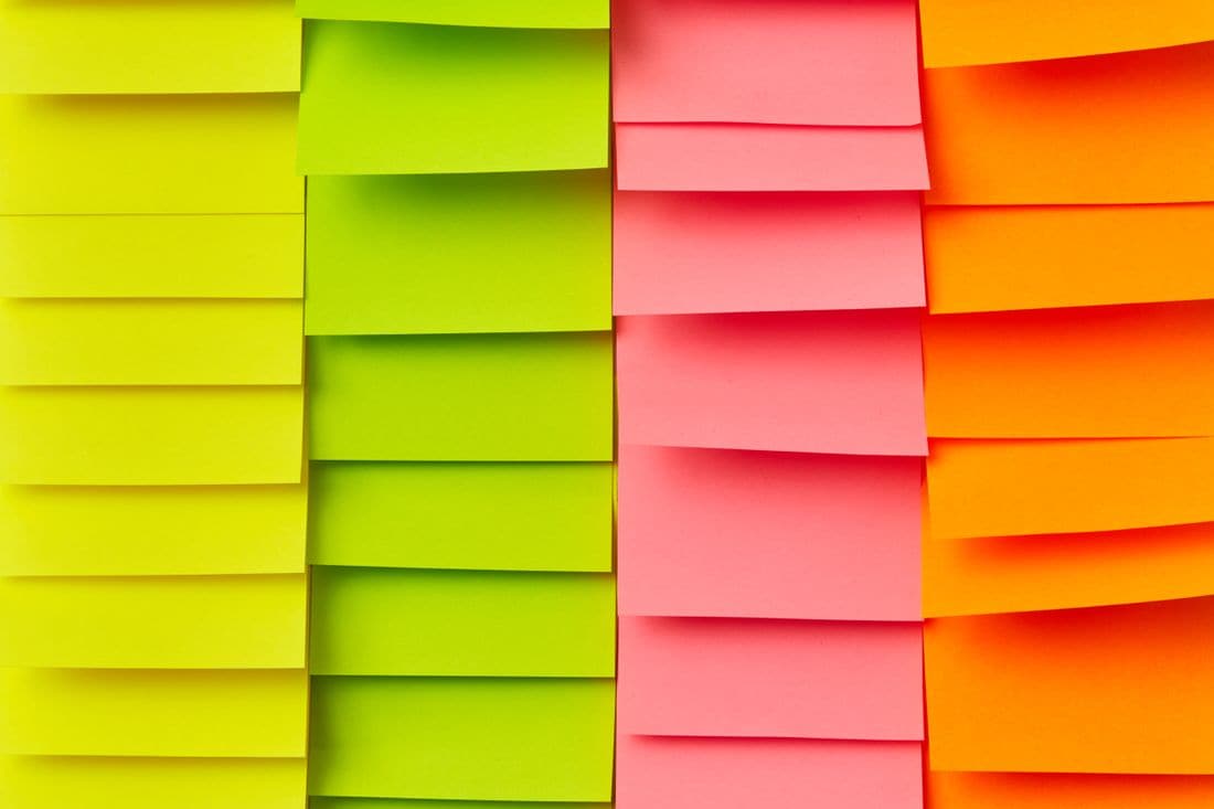 Rows of overlapping yellow, green, pink and orange sticky notes arranged in four columns
