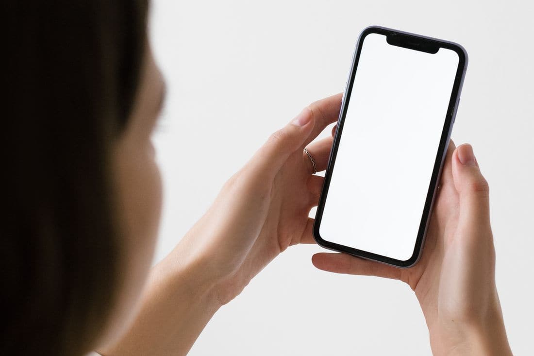 Hands holding a phone with a blank white screen