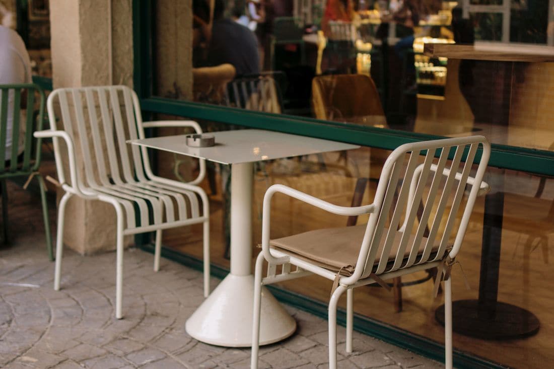 An empty table and two chairs outside a cafe window
