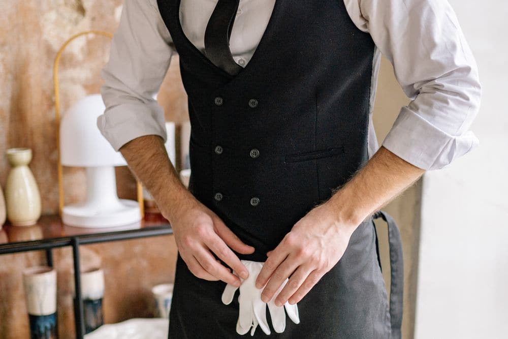 A waiter in a vest and apron getting ready for a shift