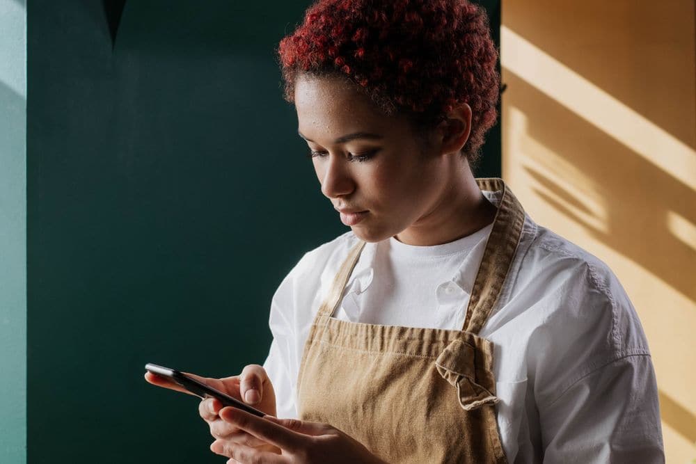 A barista in an apron checking a phone