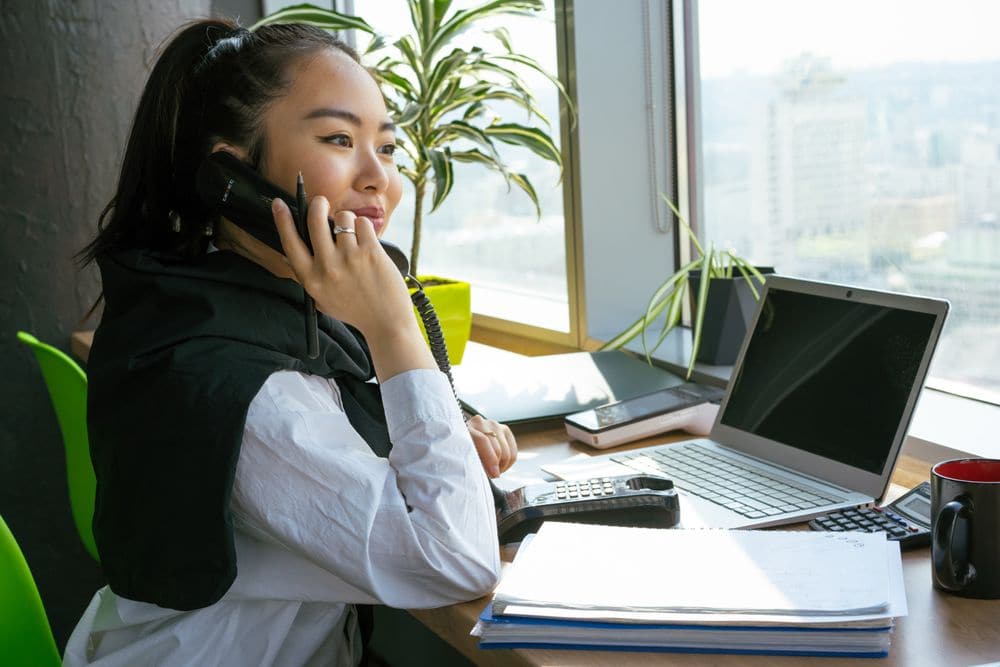 An office worker on the phone at a desk by the window