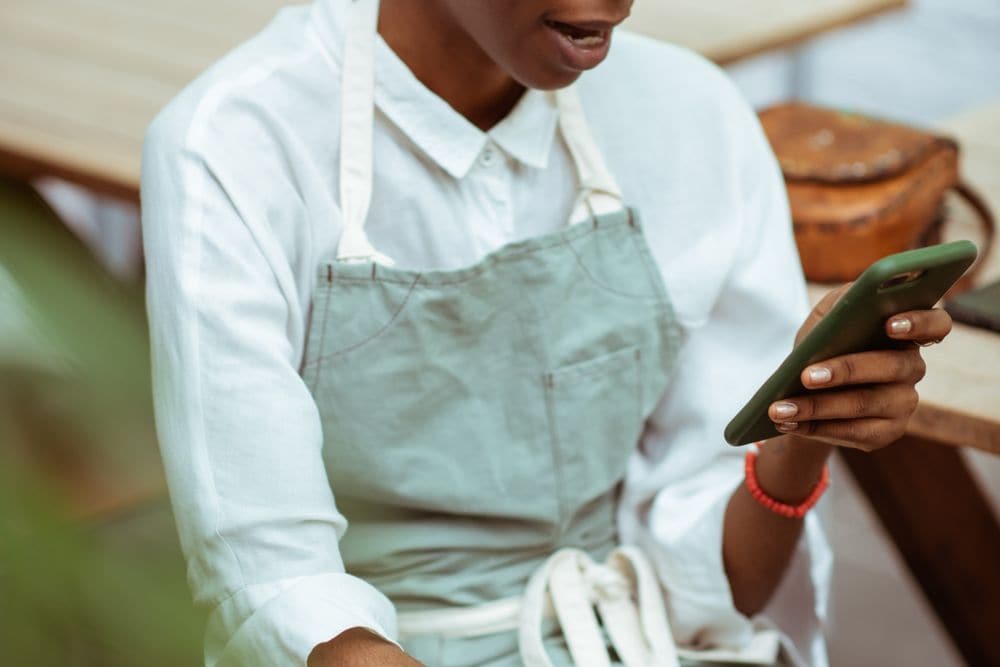 A hospitality worker in an apron reading a phone