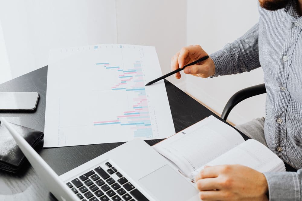 A printed chart being reviewed beside a laptop