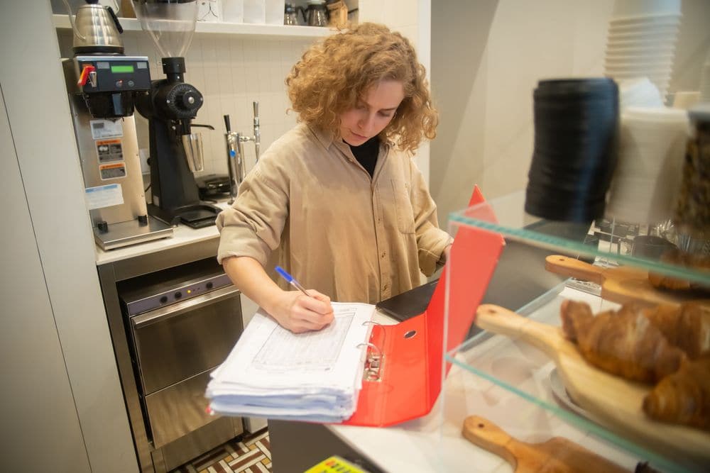 A cafe worker filling in paperwork behind the counter