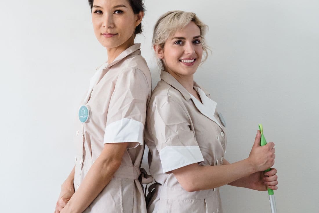 Two cleaners in uniform standing back to back
