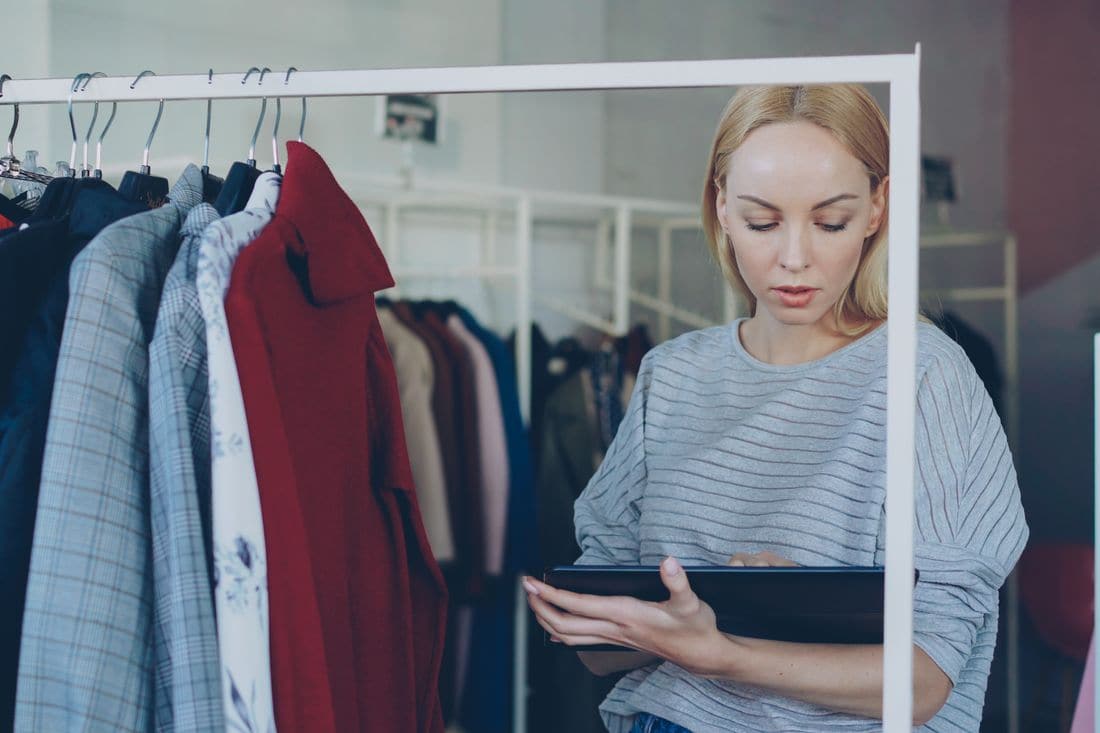 A clothing store worker checking stock on a tablet