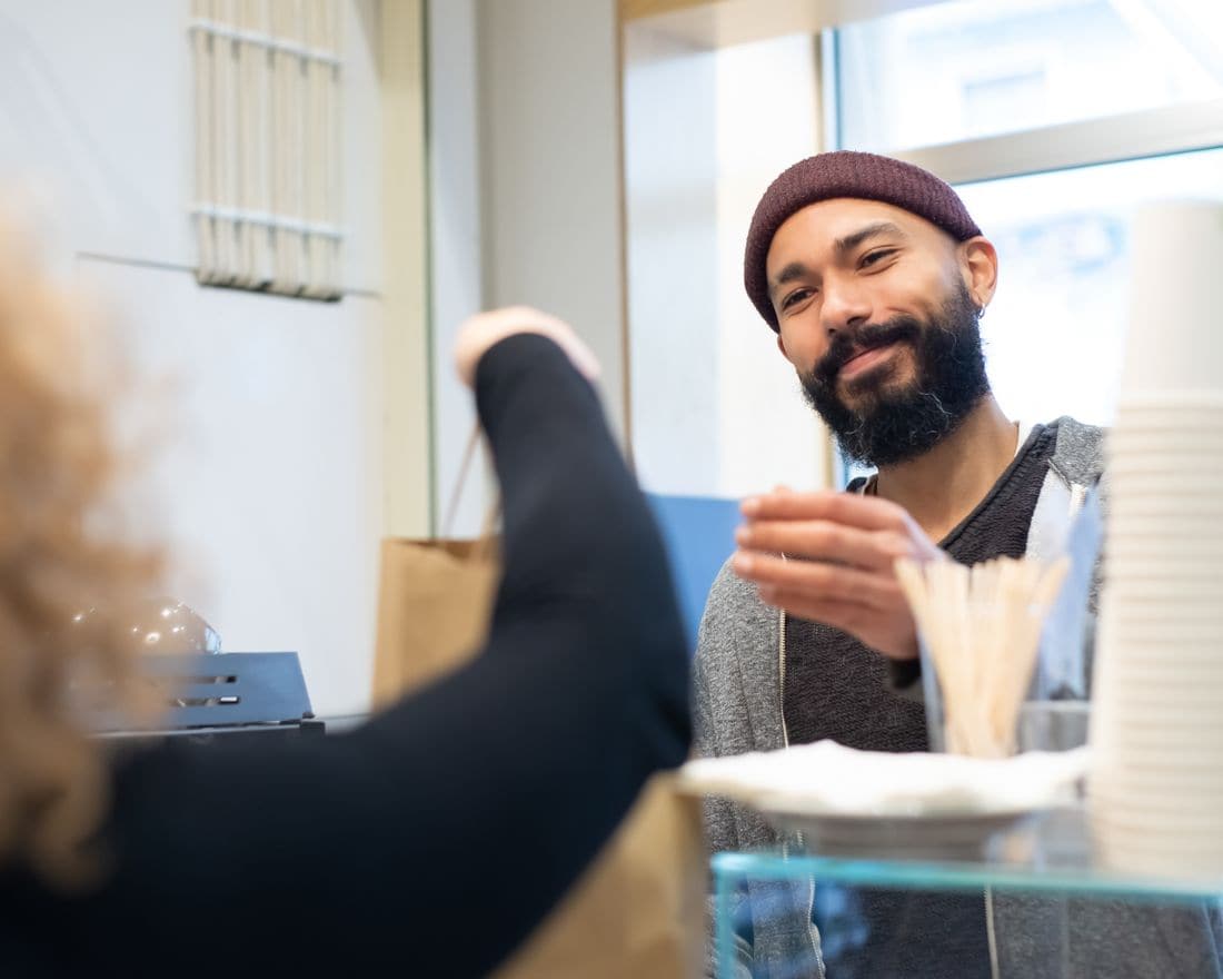 A barista handing a customer their order across the counter