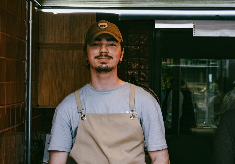A cafe worker in a cap and apron behind the counter
