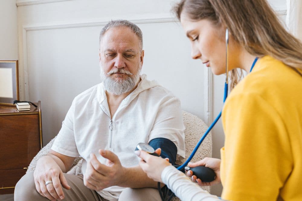 A care worker checking an older man’s blood pressure