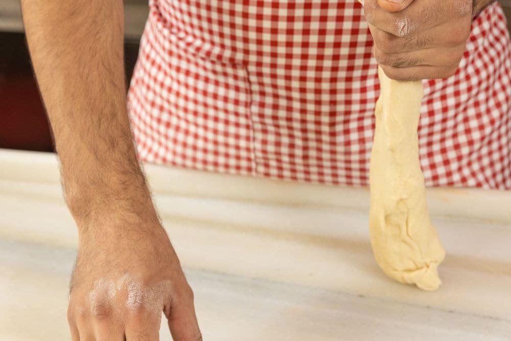 A baker shaping dough into rolls