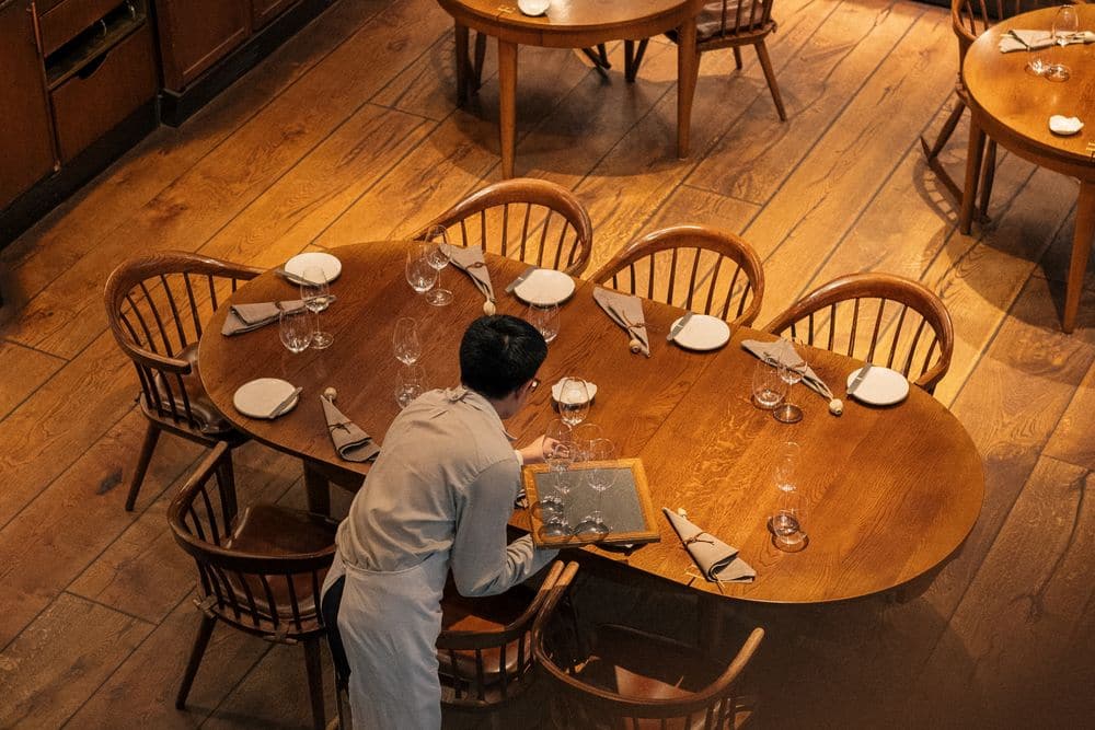 A waiter setting tables in a small bistro