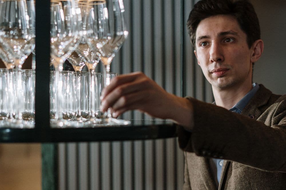 A staff member arranging wine glasses on a display shelf