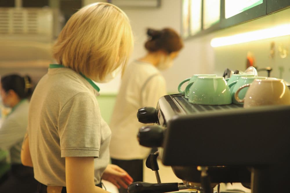 Two baristas making coffee behind the counter