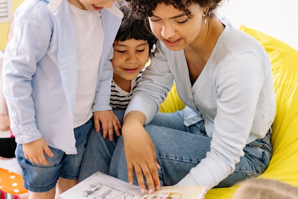 An educator reading a picture book with young children