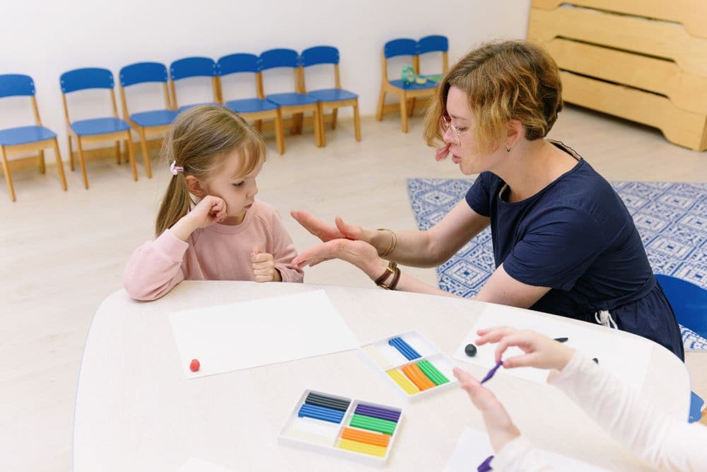 An educator helping a child with a modelling clay activity