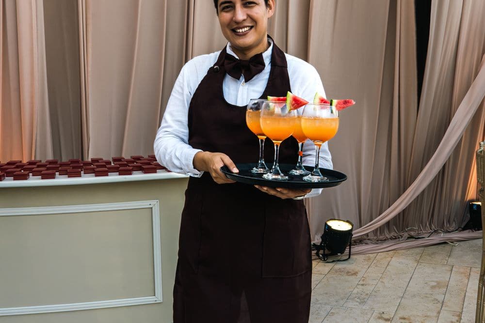 A waiter carrying a tray of drinks at a function