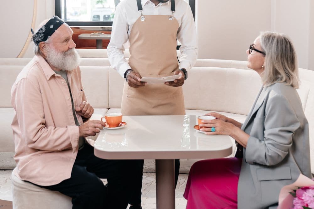 A waiter taking an order from an older couple over coffee