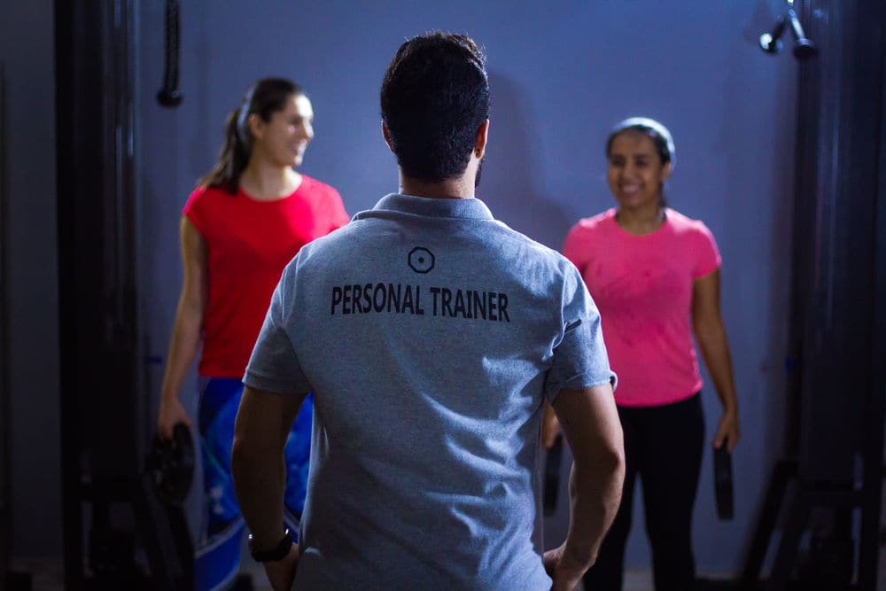 A personal trainer coaching two women in a gym