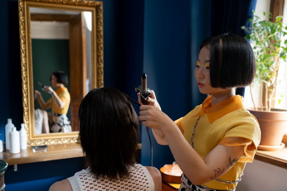 A hairdresser curling a client’s hair