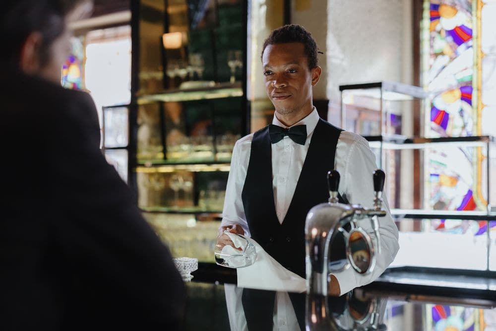 A bartender polishing a glass behind the bar