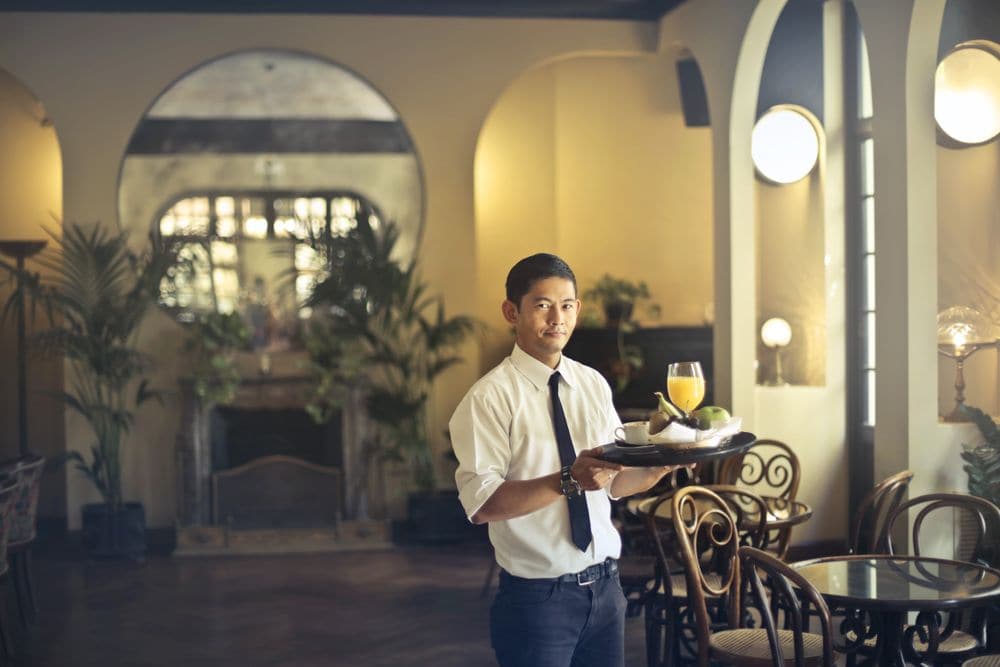 A waiter serving drinks in a warmly lit restaurant
