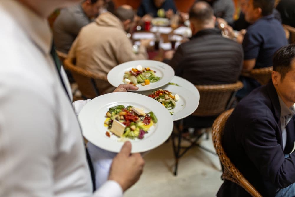 A waiter bringing salads to a table of diners