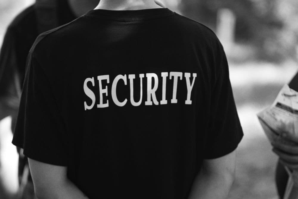 A security officer seen from behind in a security shirt