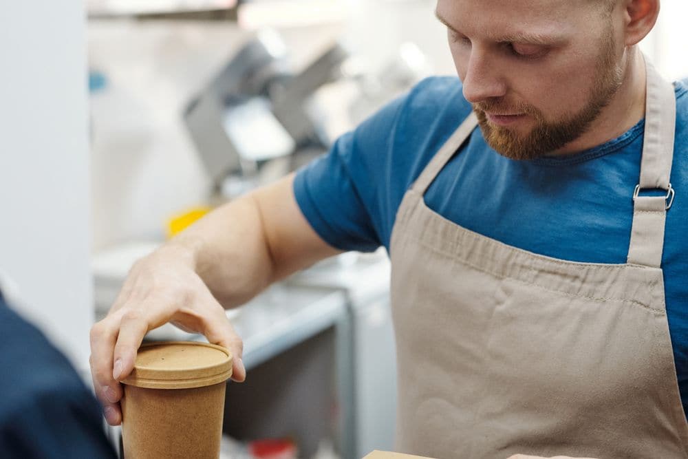 A worker closing the lid on a takeaway container